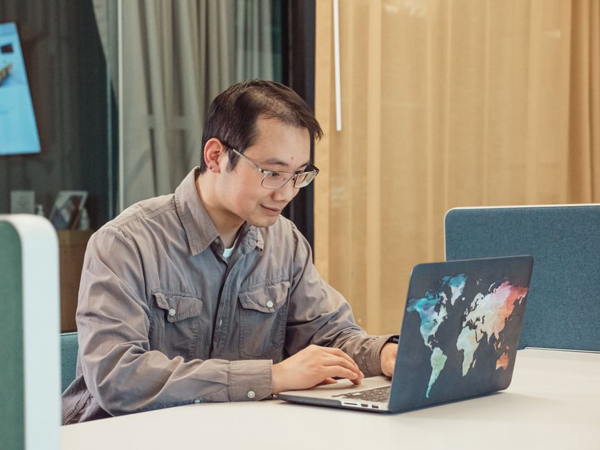 Founder working on a laptop in front of a world map, targeting prospects