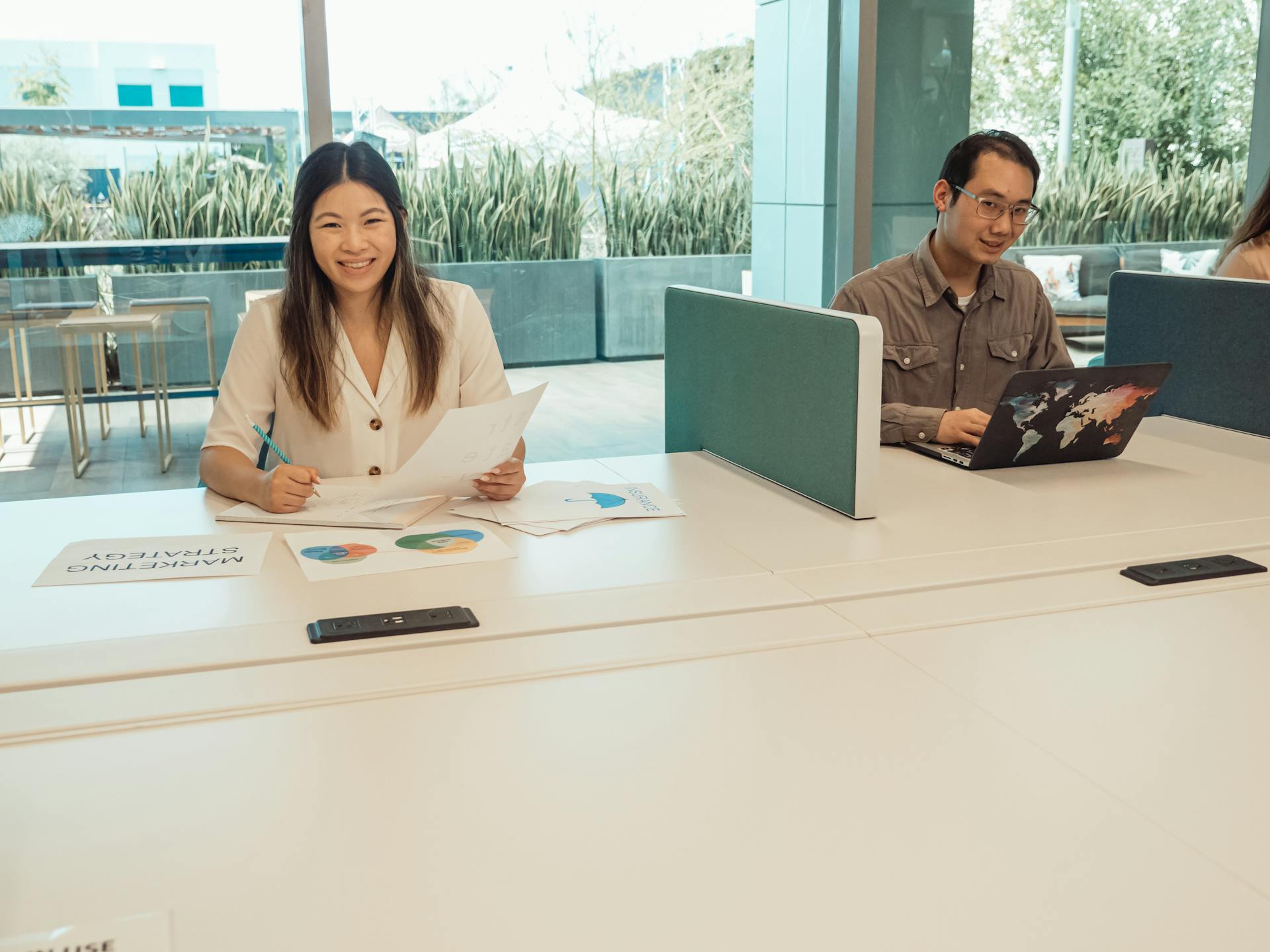 Smiling Asian colleagues working on marketing strategy in a bright, modern office.