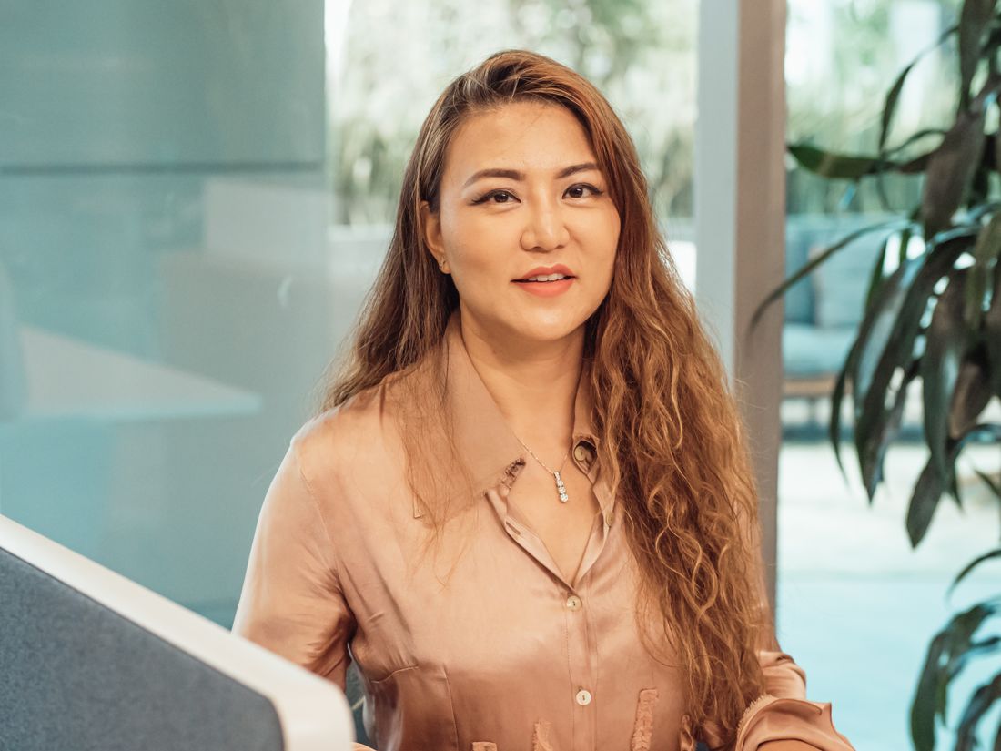 Confident woman with long hair smiling in a modern office environment