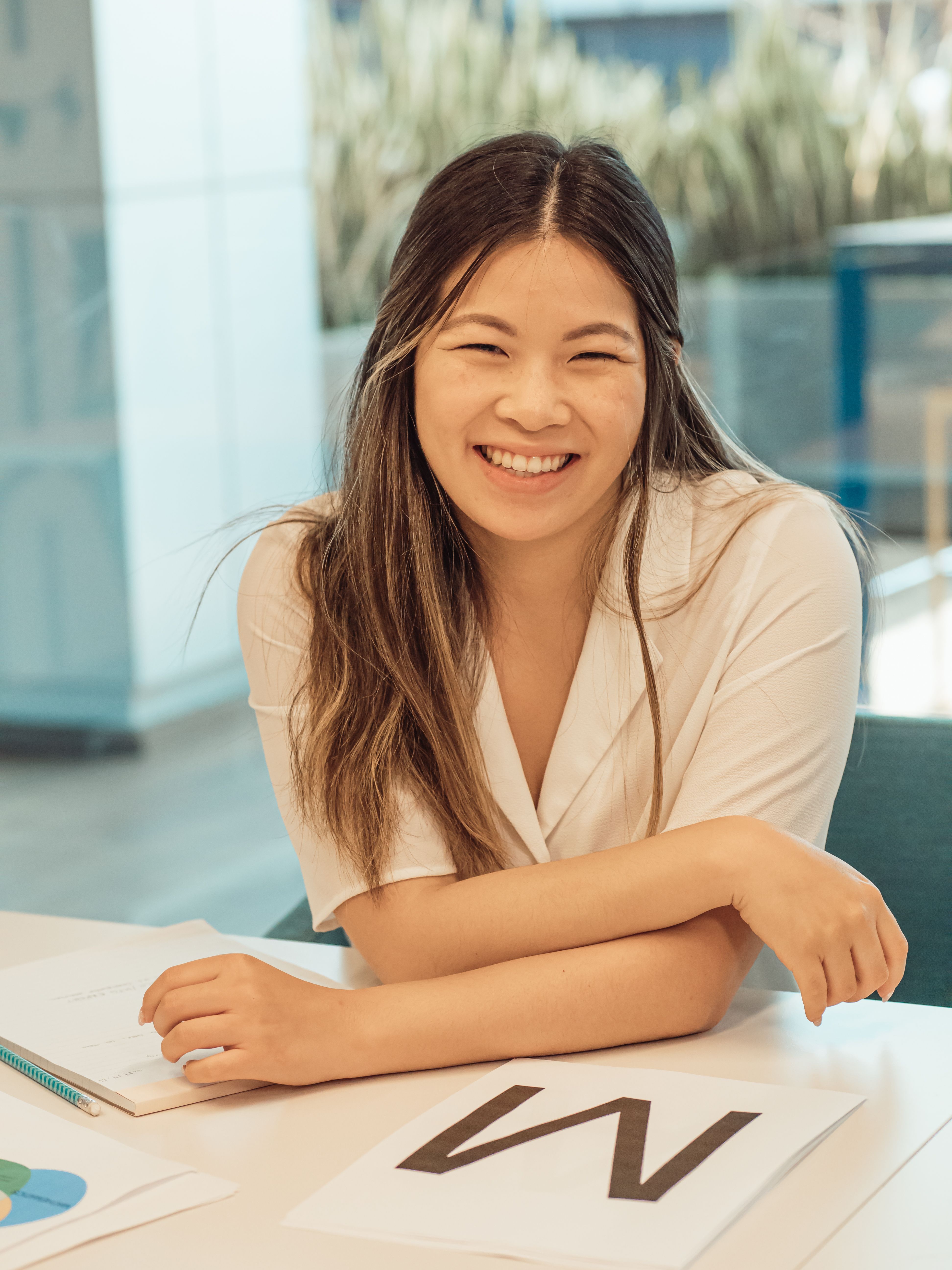 Young woman smiling in a modern office setting with documents on the table.