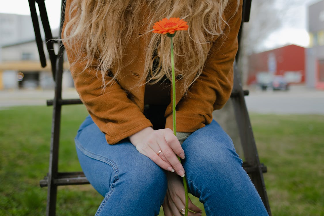 Close-Up Shot of a Woman Holding an Orange Flower