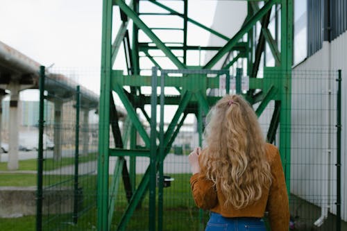 Back View of a Woman Stanidng Near Fence