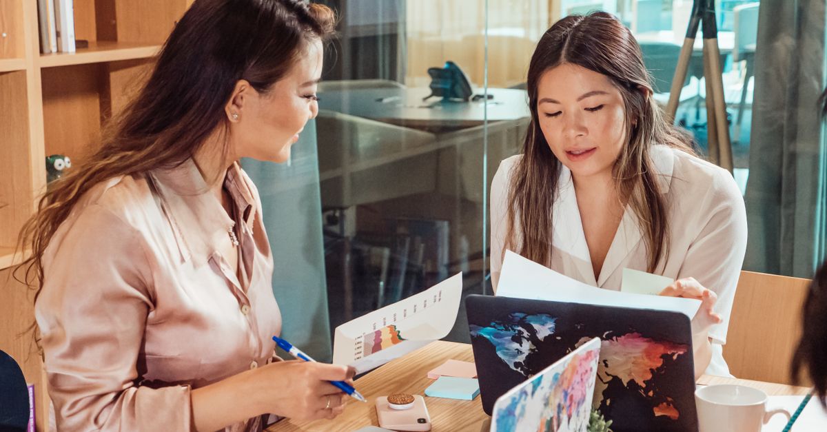 Two women collaborating in a business meeting, discussing ideas and reviewing documents.