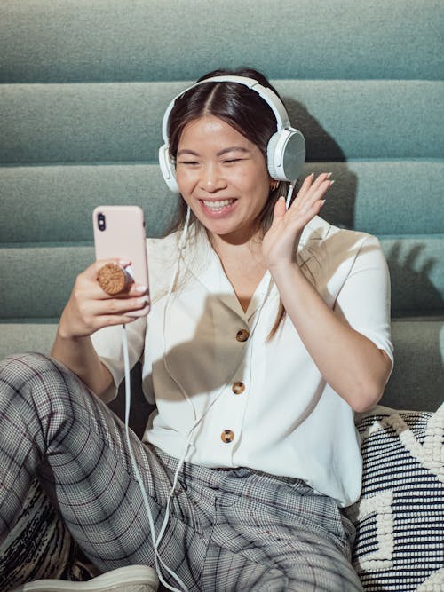 Free Woman Wearing Headphones Waving at the Cellphone Stock Photo