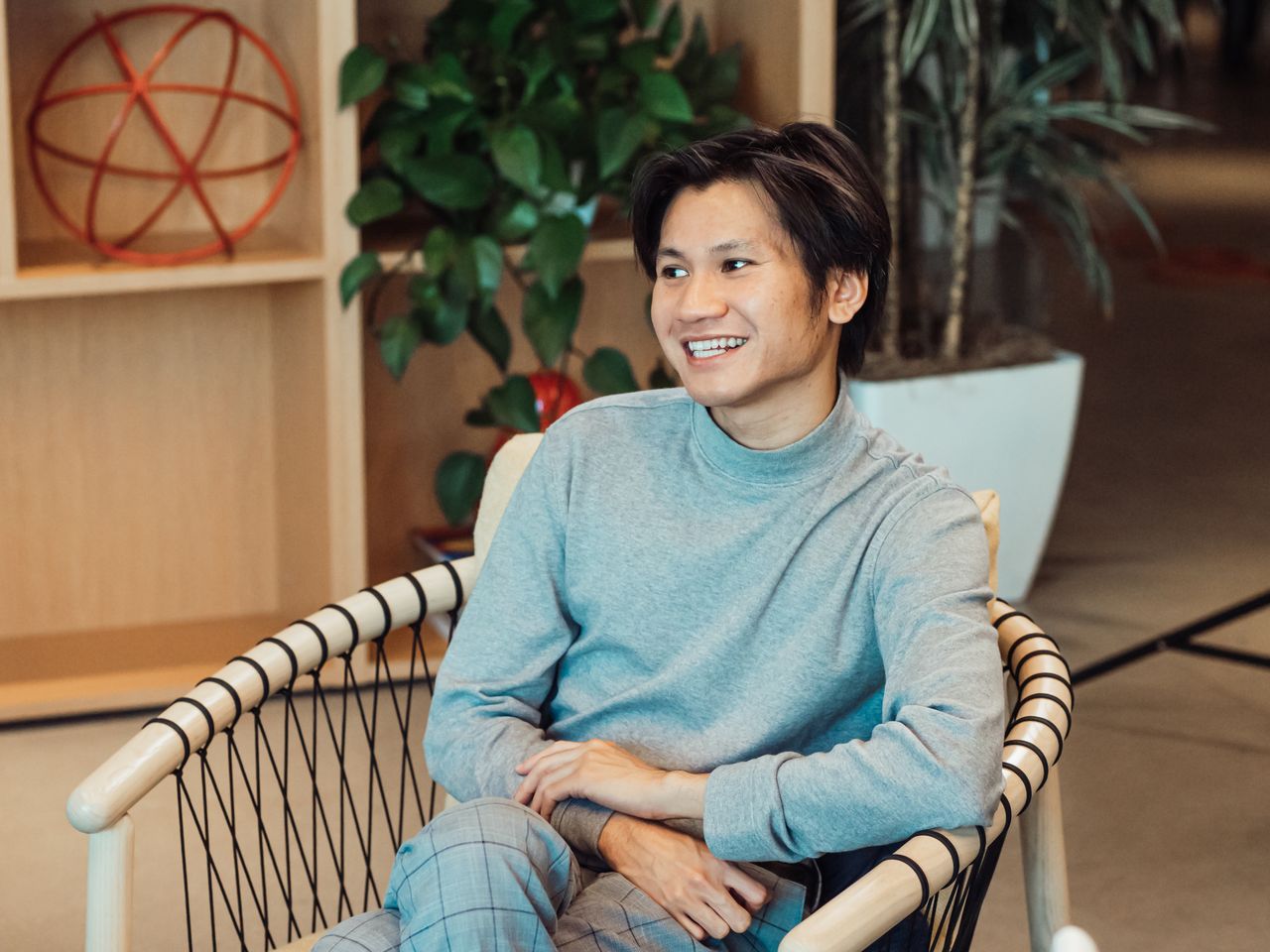 smiling man in a turtleneck sitting relaxed in a modern office with pl