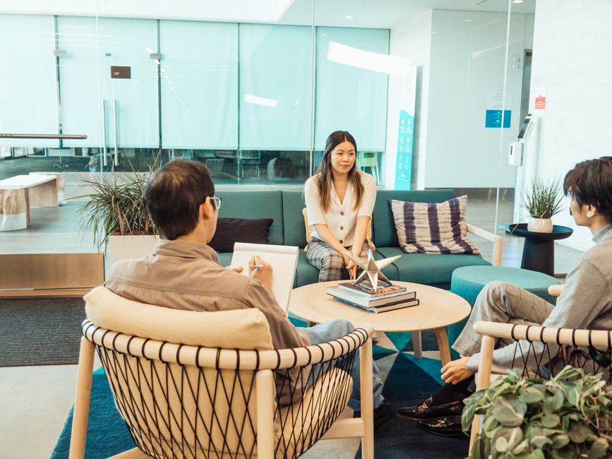 Three colleagues in a casual office setting having a discussion.