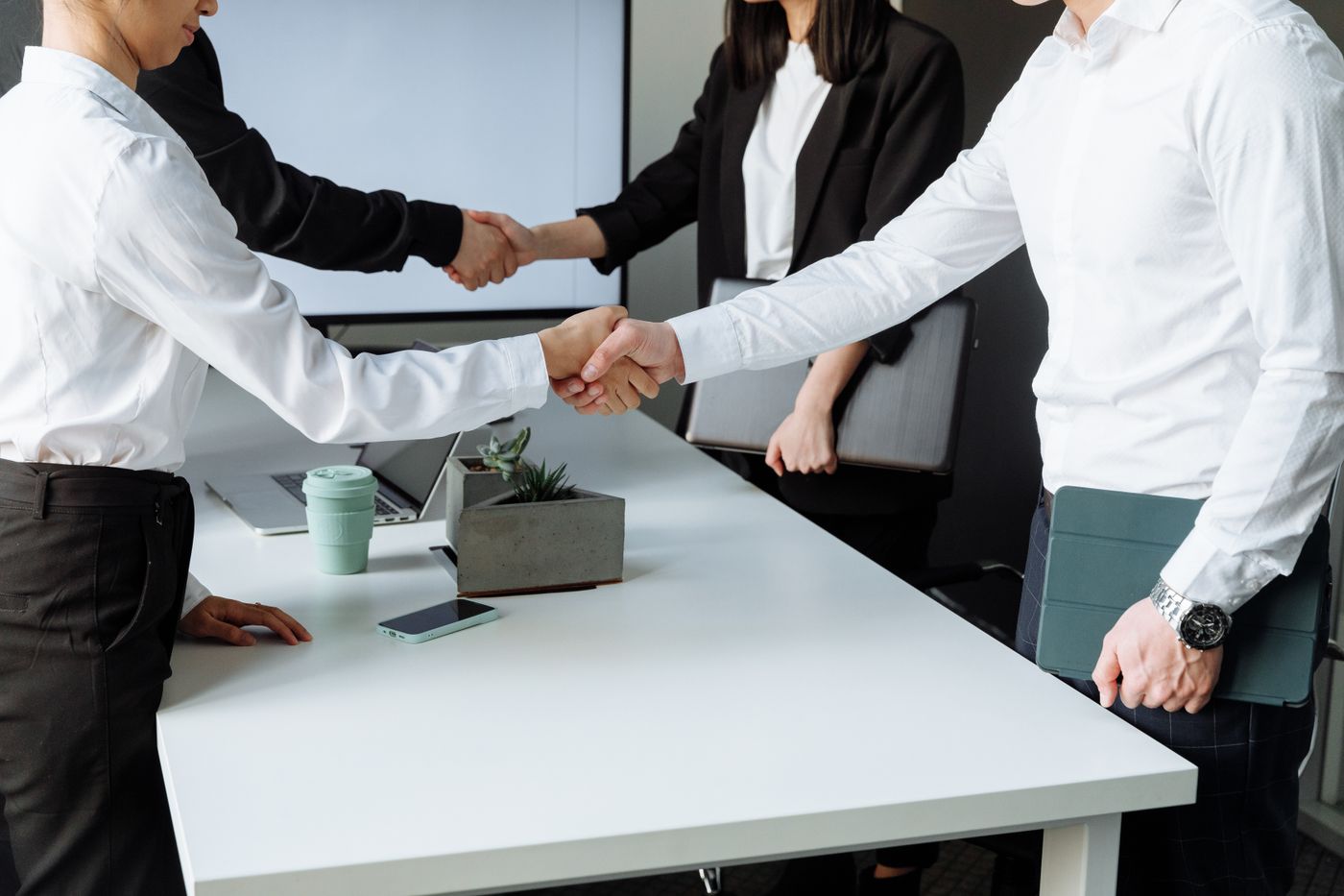Two people shaking hands over a signed agreement