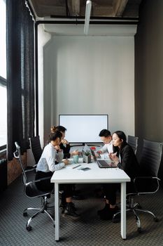 A diverse team of professionals engage in a meeting in a modern office setting.