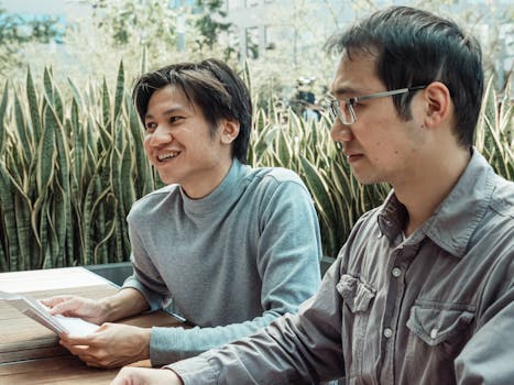 Two colleagues engaged in a productive outdoor business meeting surrounded by greenery.