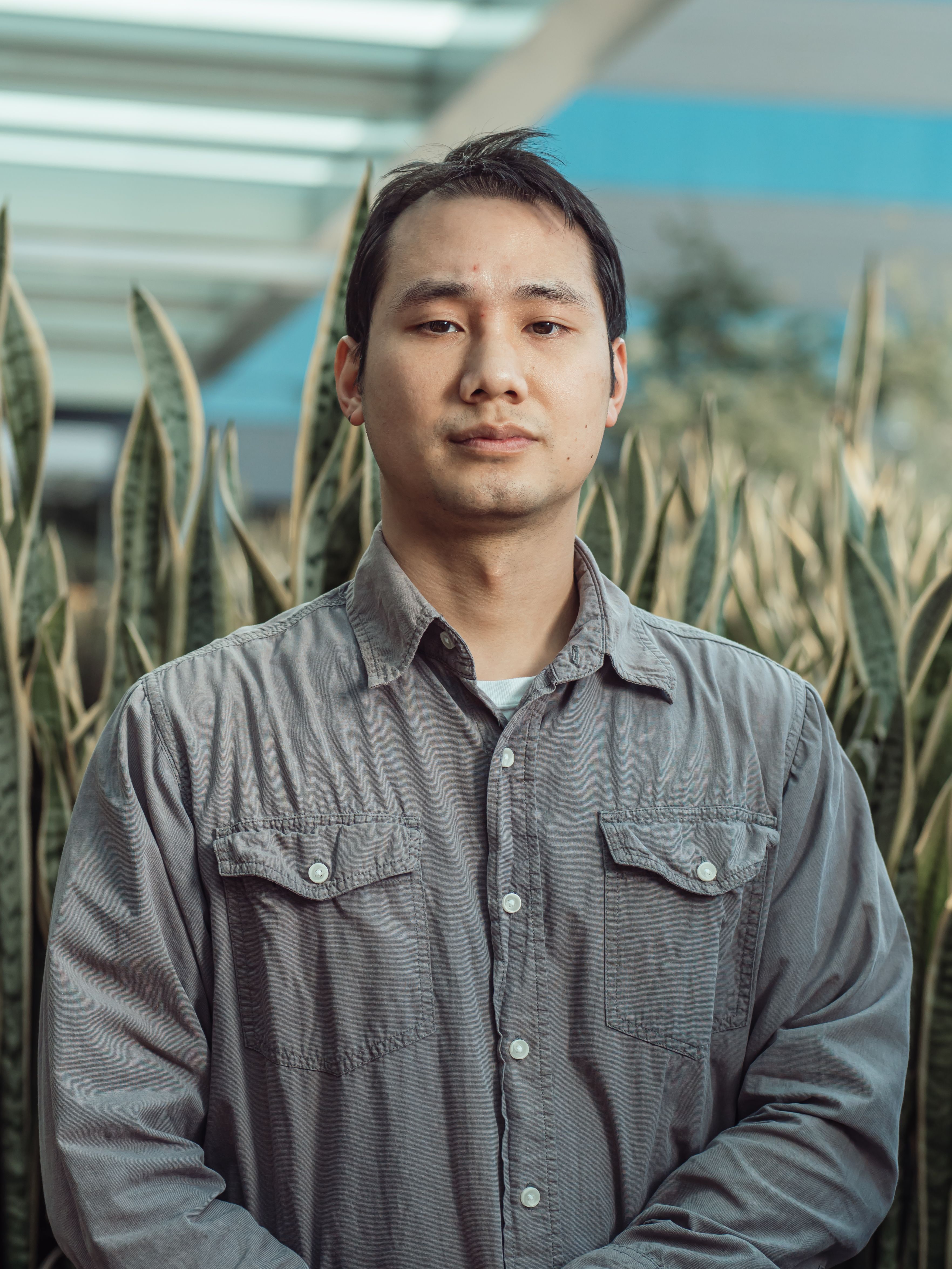 Close-up portrait of a young man in a garden setting with blurred background.