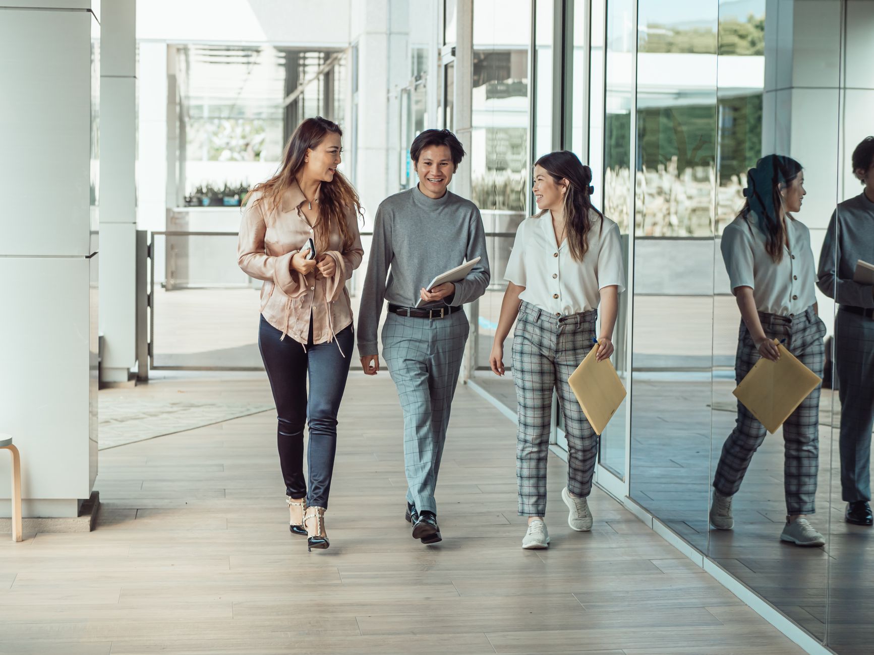 Three colleagues walking and conversing in a modern office, reflecting teamwork and collaboration.