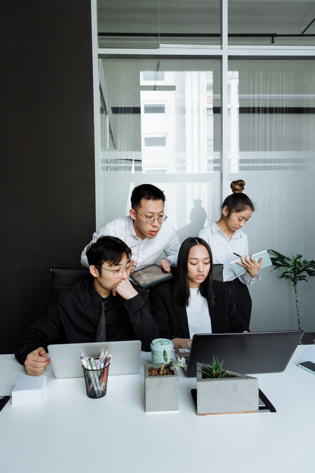 A small team gathered around one laptop, working through a problem together. Photo by Thirdman on Pexels