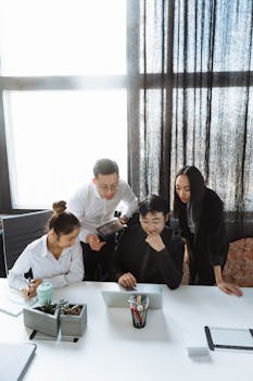 Group of professionals engaged in teamwork around a laptop, discussing a project.
