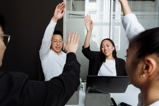 Colleagues high-fiving in an office setting, showcasing teamwork and positive collaboration.