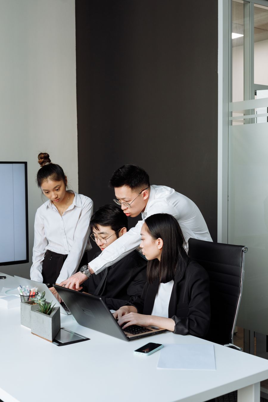 Asian business professionals reviewing a contract on a laptop