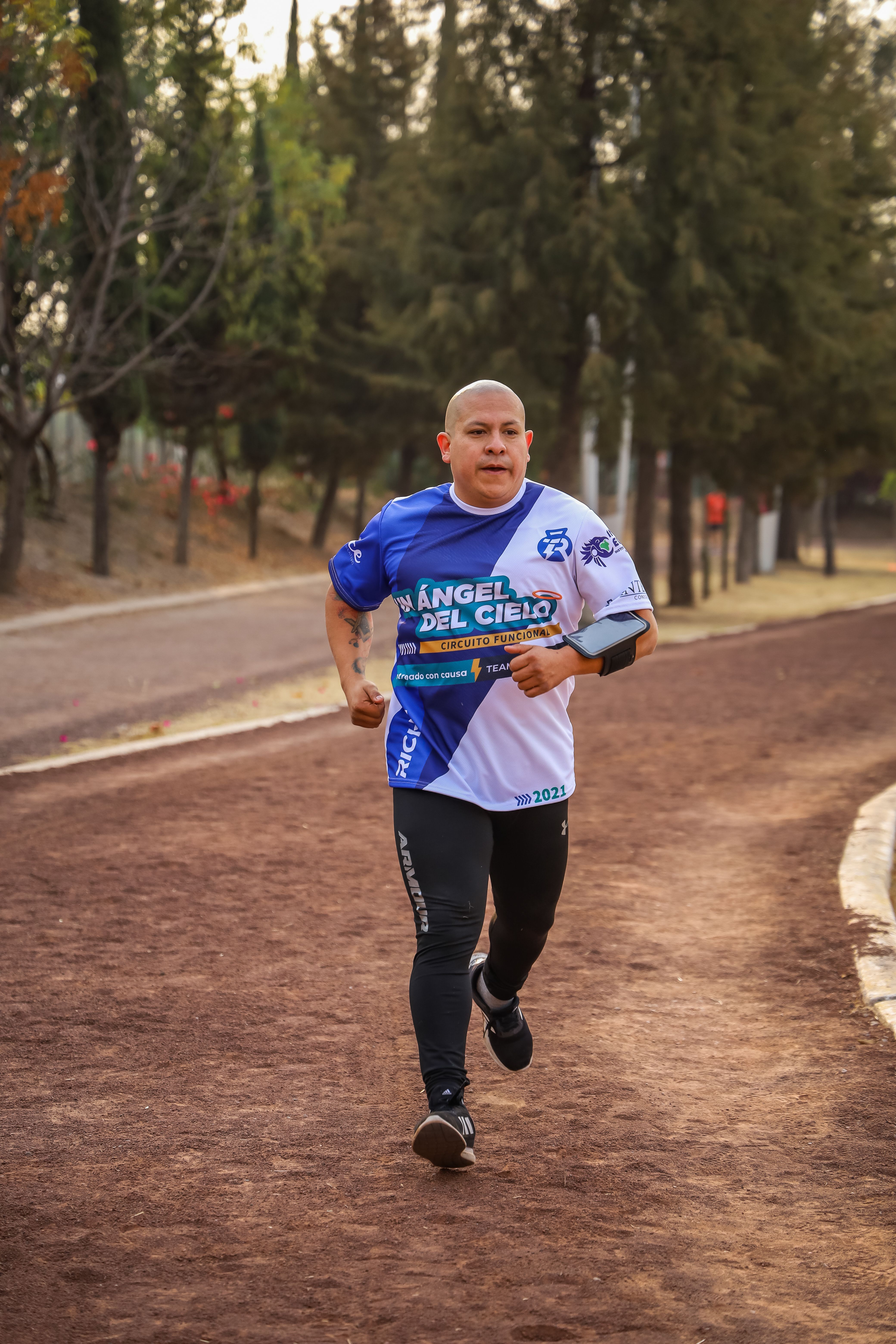 Bald man in activewear jogging on a park trail, showcasing fitness and leisure in a natural setting.