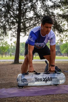 Man lifting a weighted bag during workout outdoors, showcasing strength and fitness.