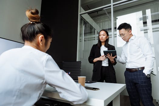 Three coworkers engaged in a discussion in a modern office setting with a focus on teamwork.