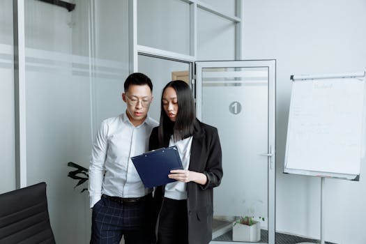 Two business professionals reviewing documents in a modern office setting.