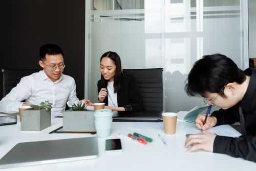 Free Professionals collaborating at a modern office table, working on documents and discussing ideas. Stock Photo