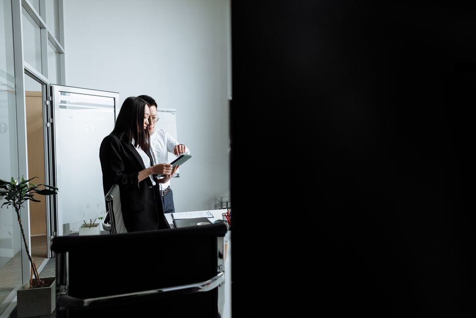 Two young professionals collaborating and discussing work in a modern office setting.