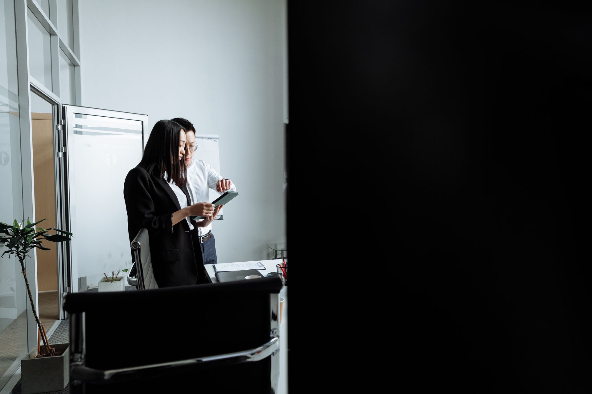 Two young professionals collaborating and discussing work in a modern office setting.