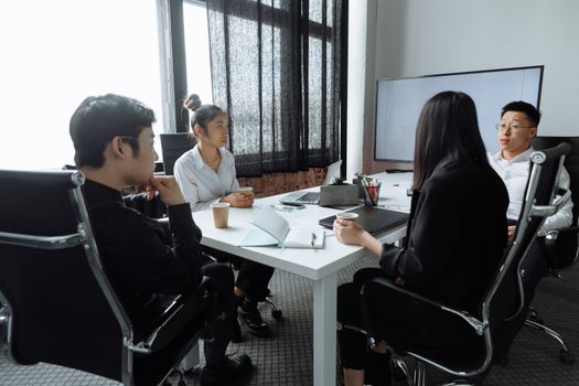 A diverse group of professionals engaged in a serious business meeting in a modern office setting.