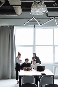 Group of colleagues collaborating on laptops in a stylish, modern office setting.