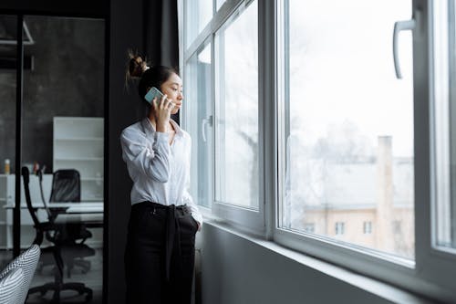 Woman Talking on the Phone While Looking Outside