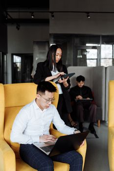 Group of colleagues working together with laptops and tablets in a modern office environment.