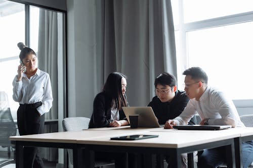 Young Business People Working and Discussing In Front of a Laptop Inside an Office