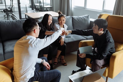 A diverse team of professionals collaborating and fist-bumping in a modern office setting.