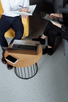 Adults collaborating in an office using laptop and tablet, emphasizing teamwork and digital tools.