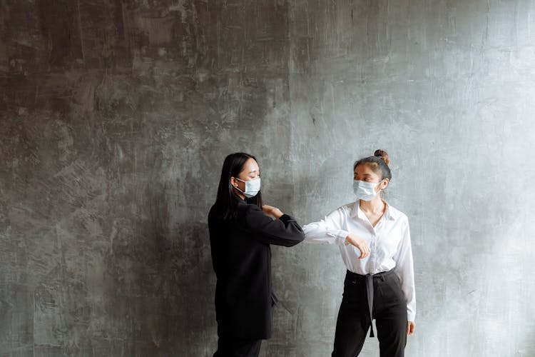 
Women Wearing Face Masks Touching Elbows