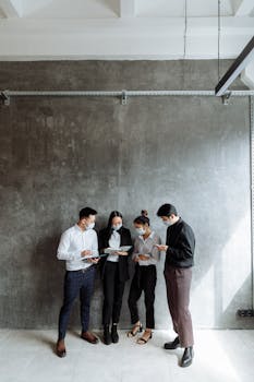 A group of professionals discussing work while standing in a modern office.