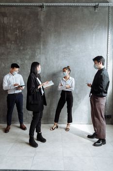 Business team of four wearing face masks during a meeting in a modern office.