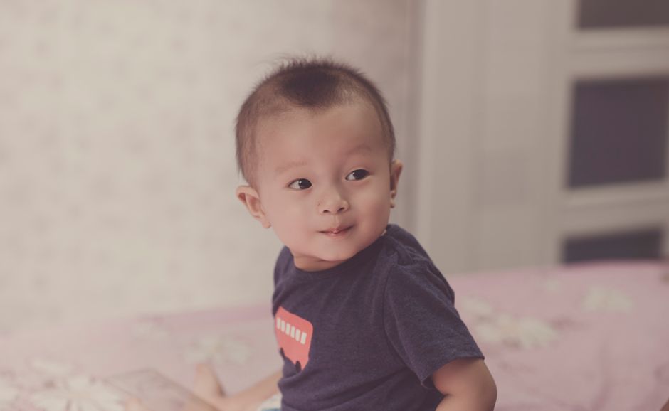 Charming portrait of a baby boy with curious expression captured indoors.