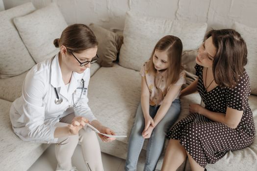 Doctor explaining diagnosis to mother and daughter in office.