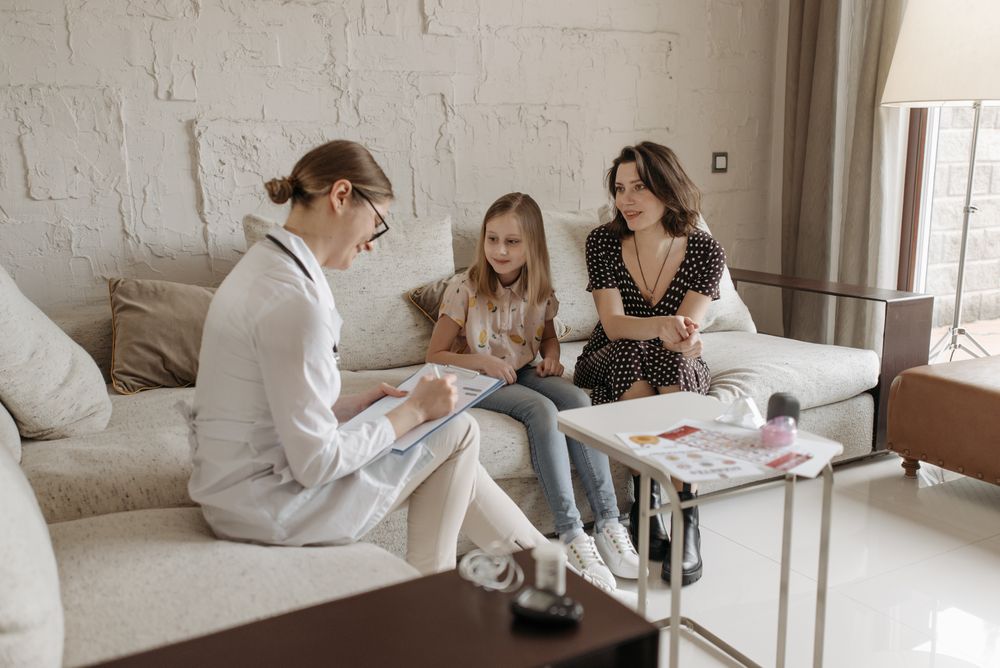 Doctora conversando con una madre y su hija durante una consulta.