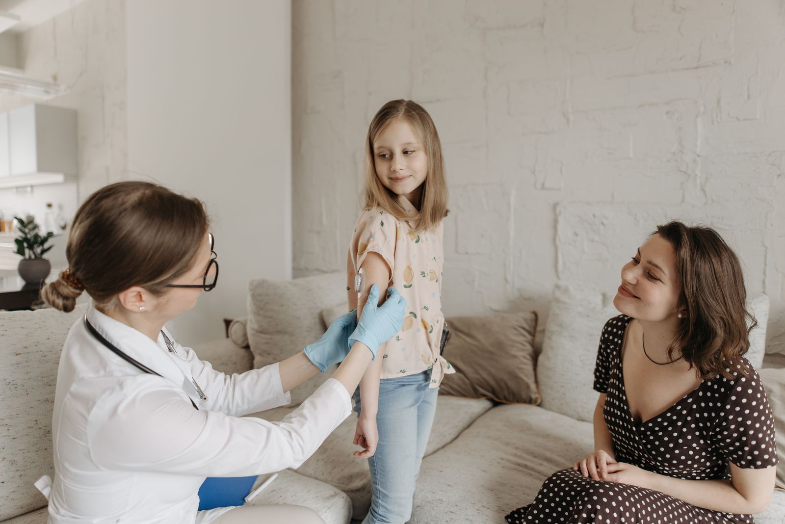 Pediatric healthcare professional supporting a school-age child and her mother at home