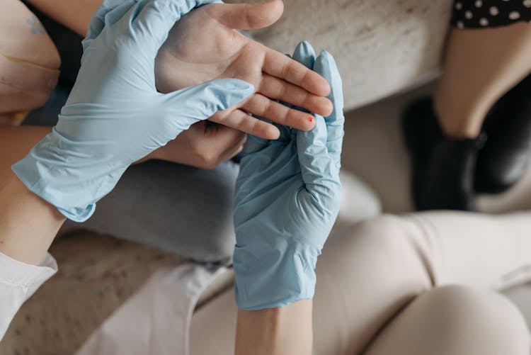 Hands Wearing Blue Gloves Holding  A Hand With Blood On Finger