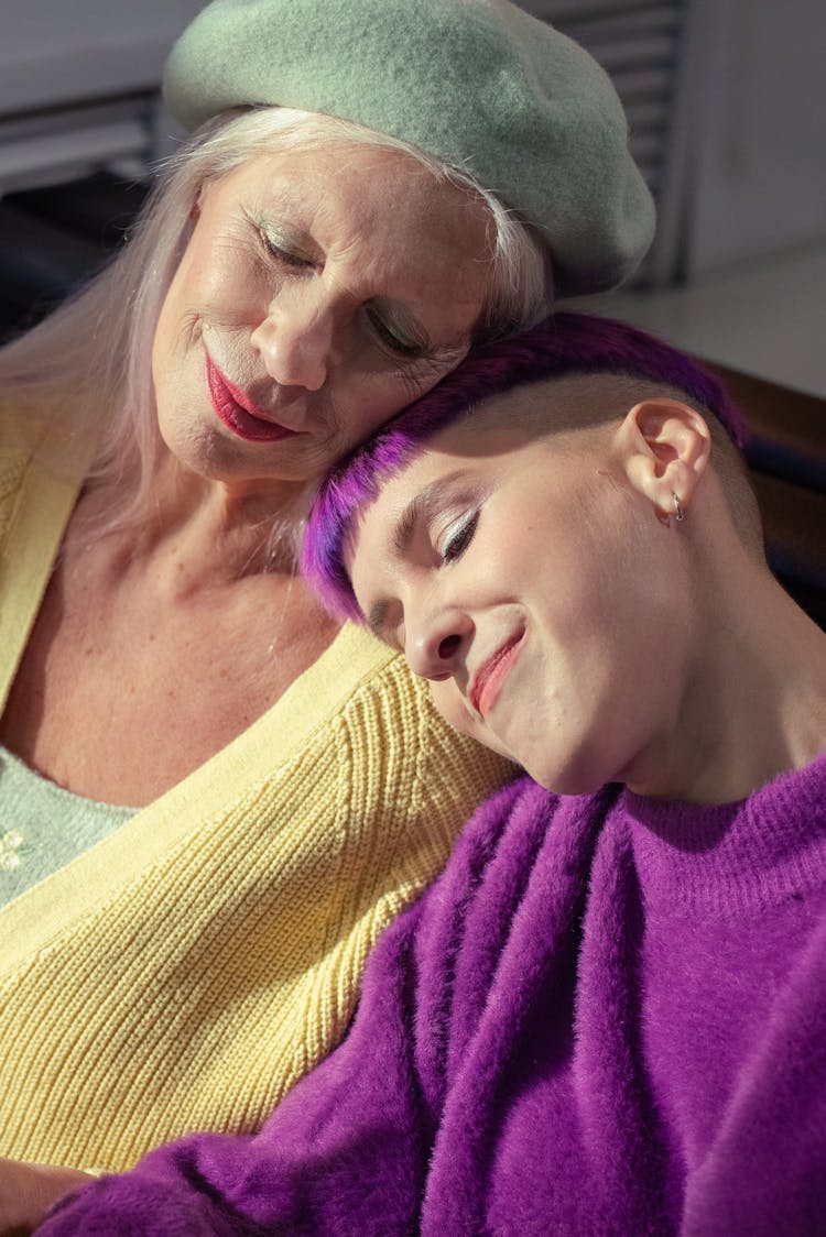 Elderly Woman And Young Woman With Purple Hair Sitting Close Together 