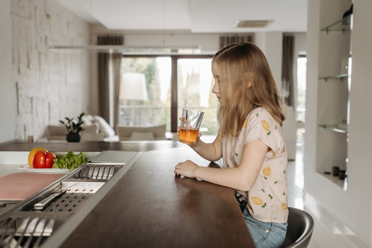 A Girl Drinking A Glass Of Juice