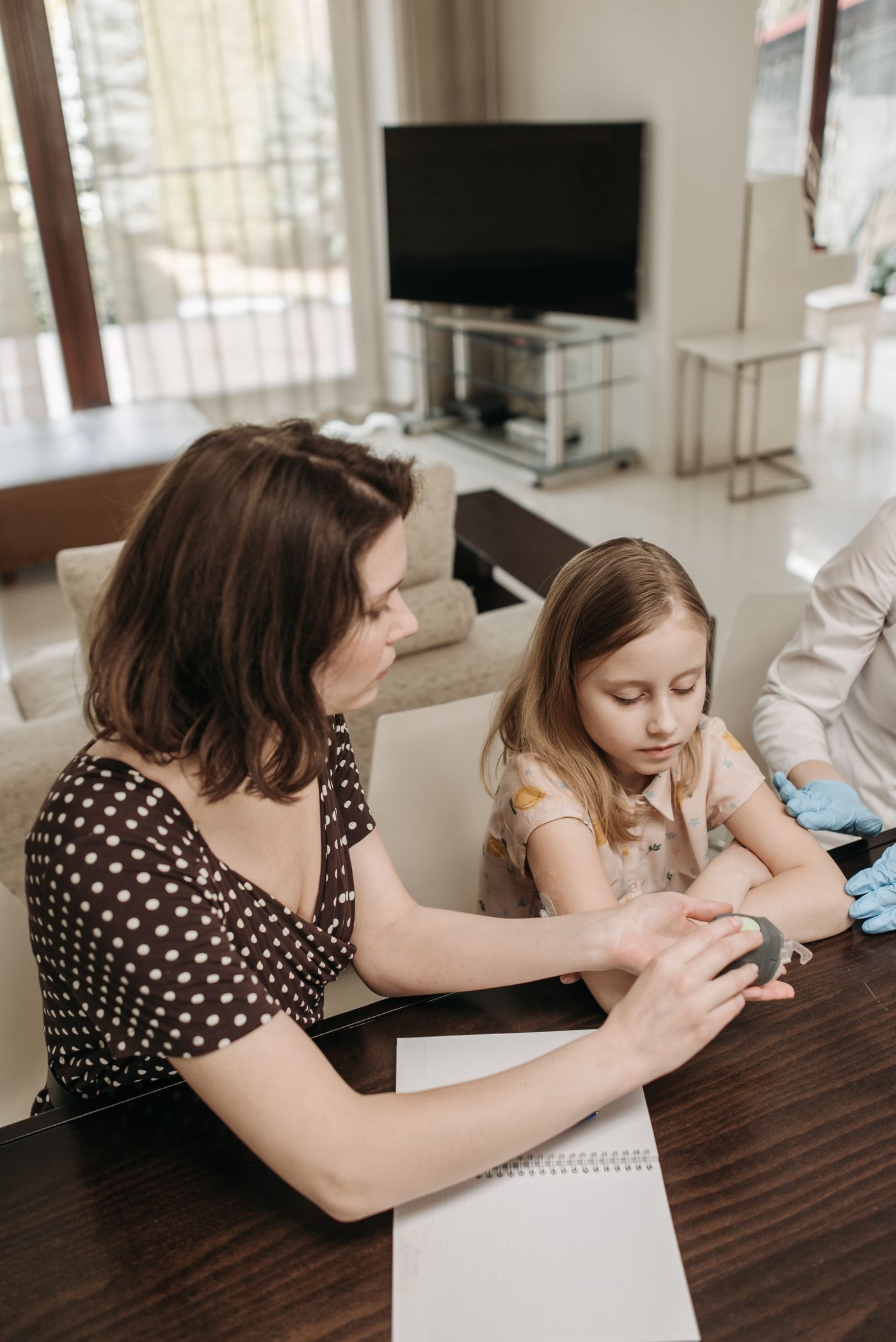 A school-age child at home with a parent and pediatric healthcare professional during a care consultation