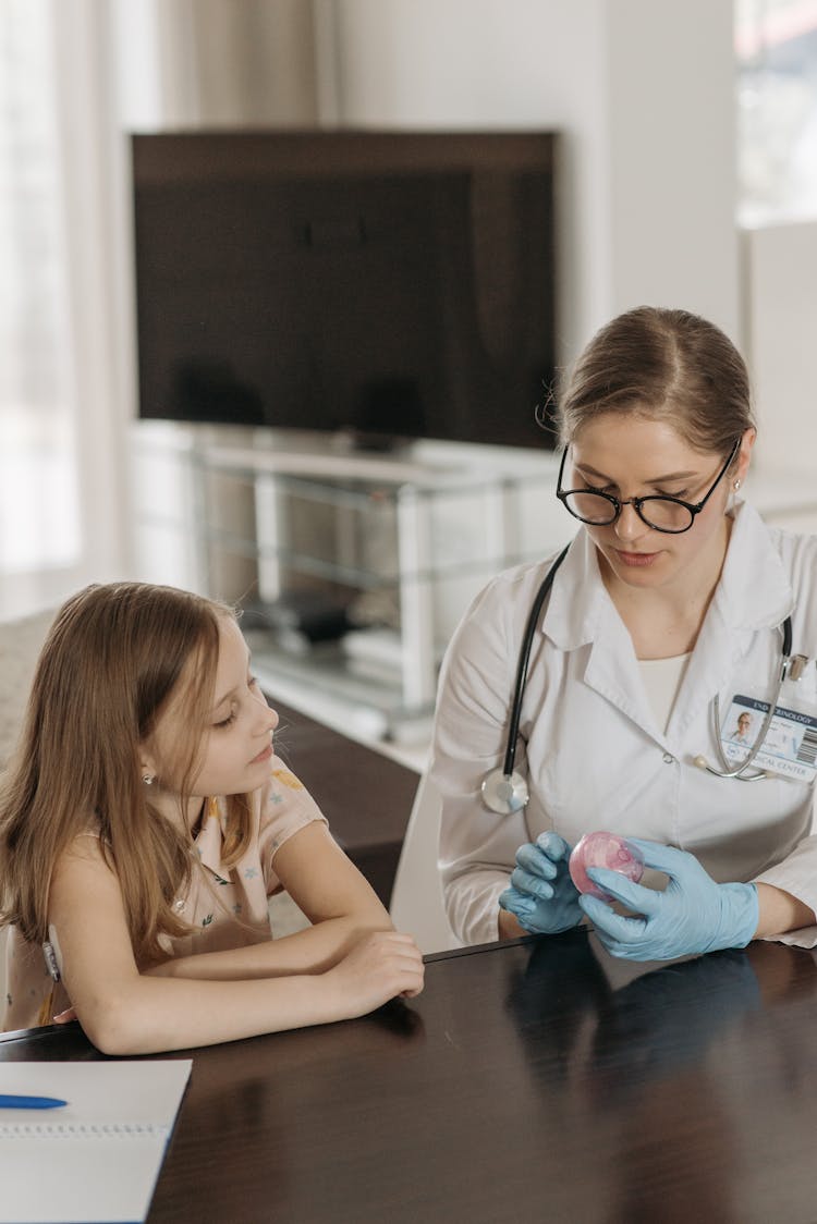 A Doctor And A Little Girl Sitting At The Table At Home 