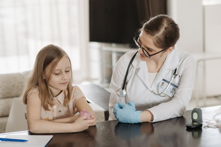 Smiling Doctor Sitting With Girl By Table