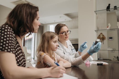 A Doctor Talking to a Girl about Diabetes while Holding a Glucometer during a Home Visit 