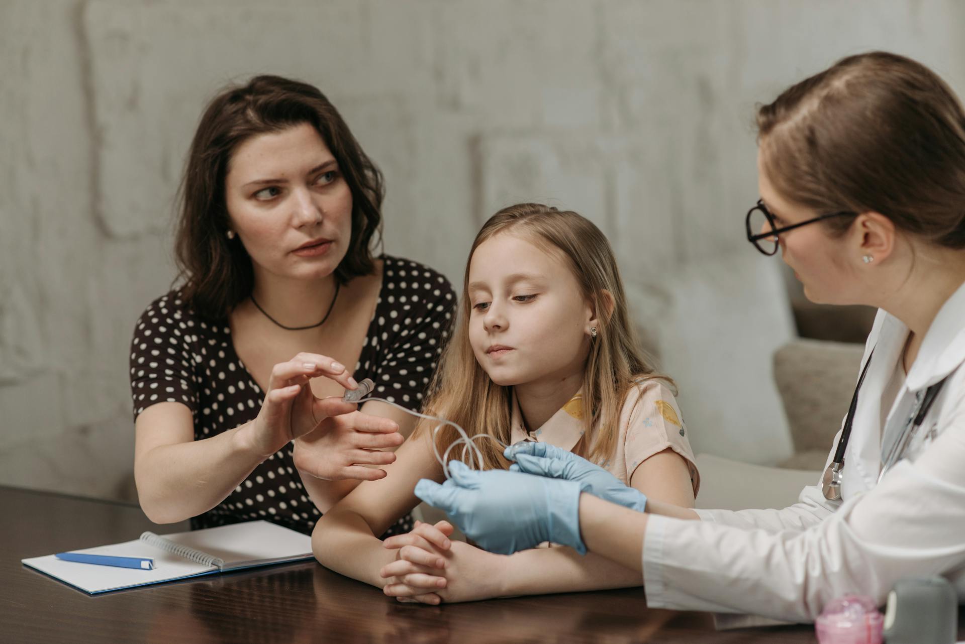 Doctor Sitting at the Table with a Mother and Daughter during a Home Visit