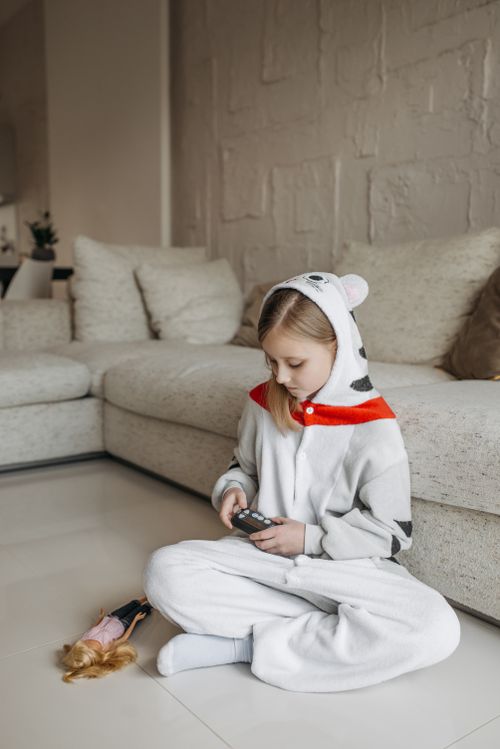 Free Young girl in animal onesie checks blood sugar with glucometer at home. Stock Photo