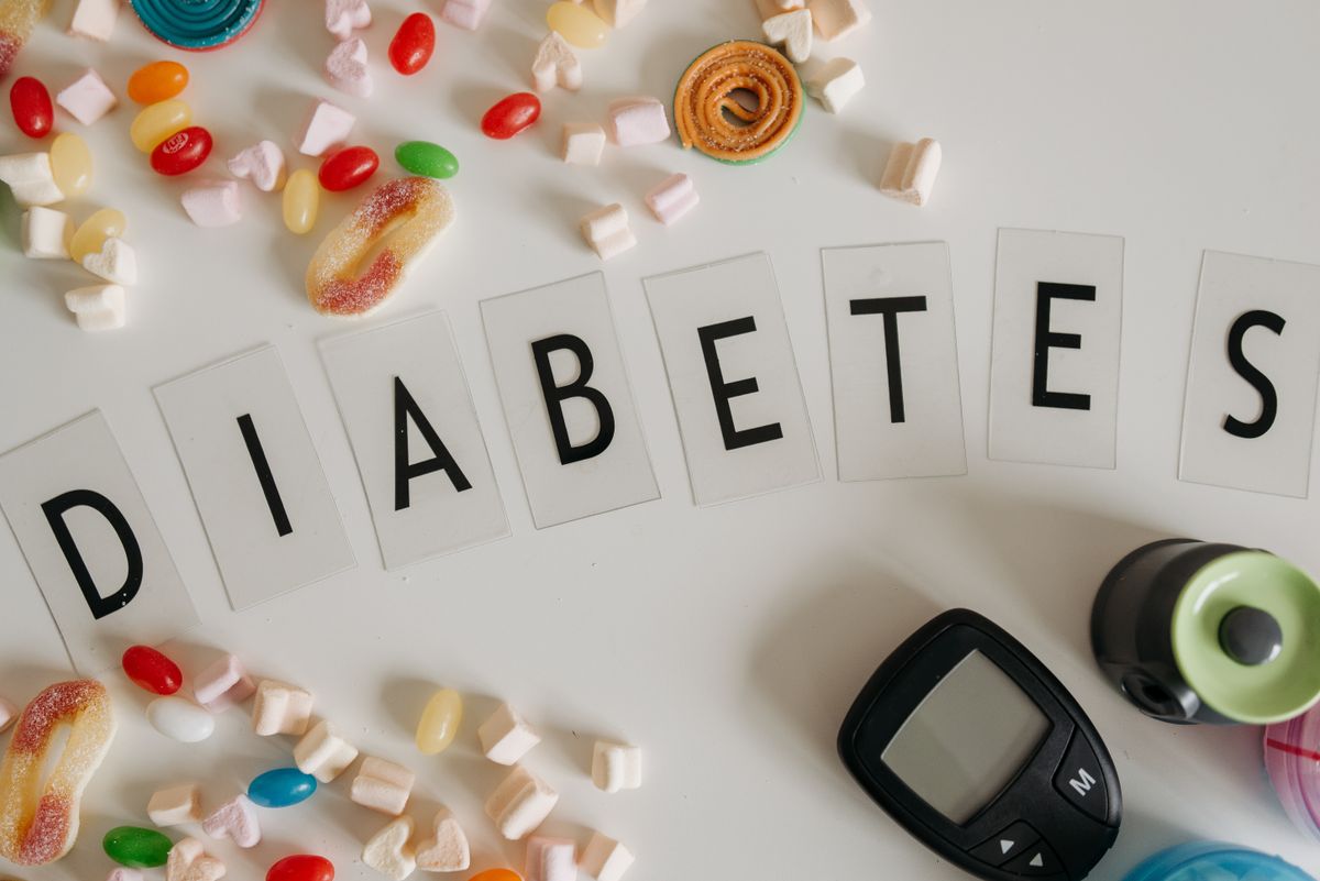 A diabetes awareness concept image featuring colorful candies and a glucose meter on a white background.